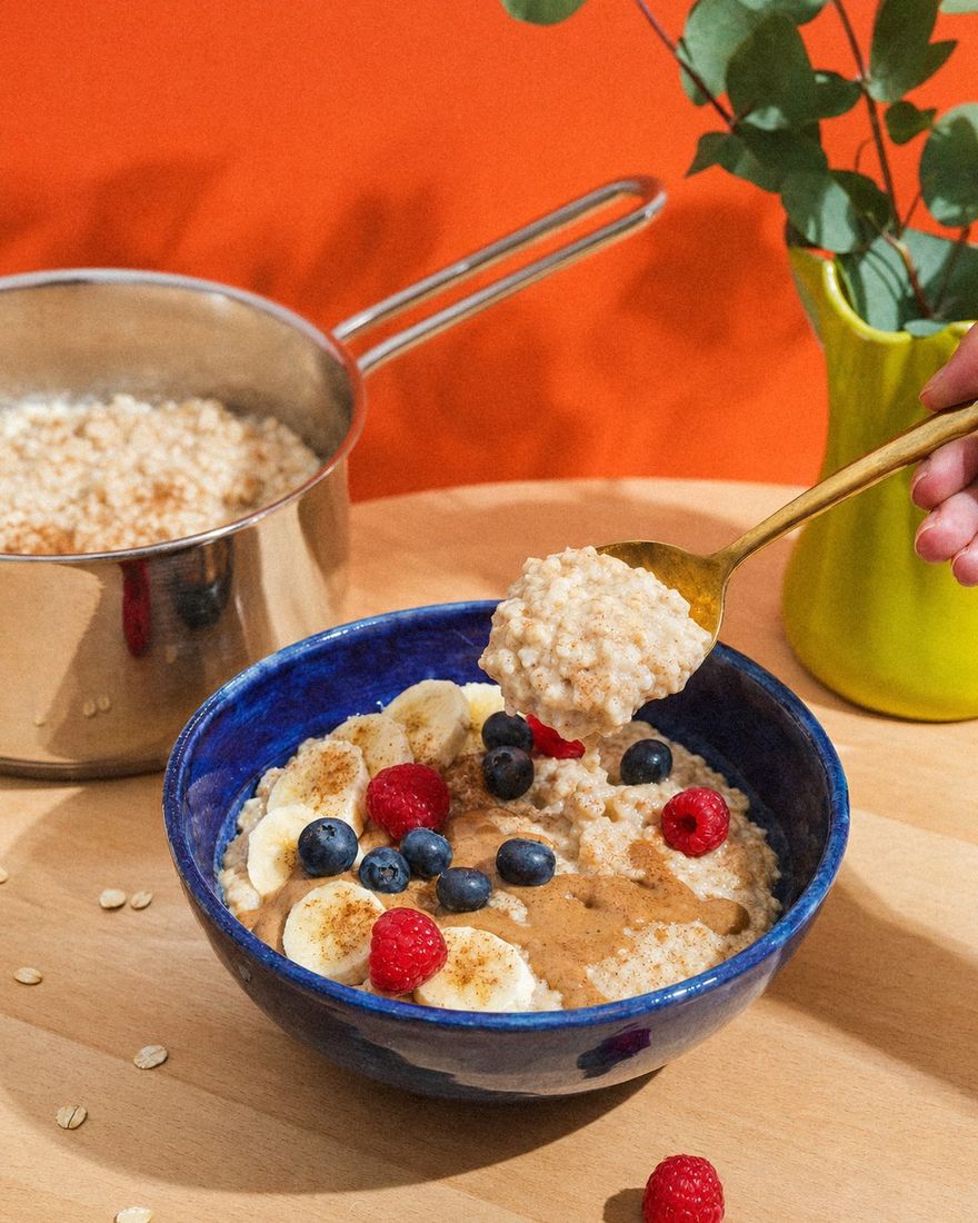 Cremiges Porridge wird in die cobaltblaue Kinderschale serviert, mit Banane und Beeren
