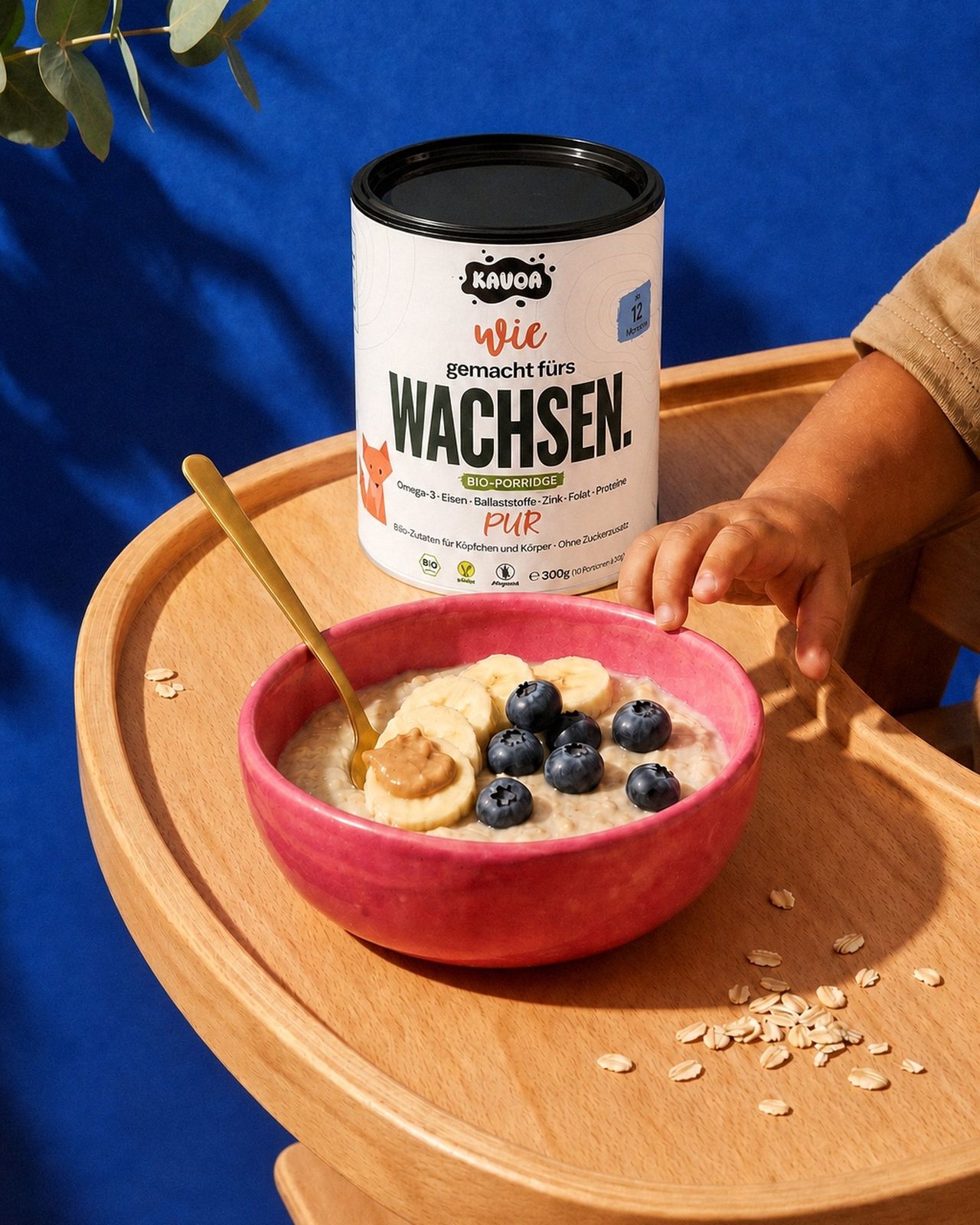 Kleinkind greift nach dem Löffel neben einer Schüssel Kavoa Bio-Porridge